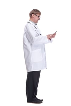side view. smiling doctor with a smartphone looking at you .isolated on a white background.