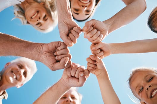 Happy big family, hands and fist bump in teamwork, motivation or unity for support or trust on sky background. Low angle of people smile touching in team collaboration, community or outdoor goals.
