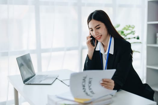 Beautiful young teen asian businesswoman using laptop computer and paperworks with planning working on financial document, tax, exchange, accounting and Financial advisor.