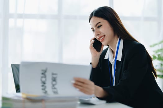 Beautiful young teen asian businesswoman using laptop computer and paperworks with planning working on financial document, tax, exchange, accounting and Financial advisor.