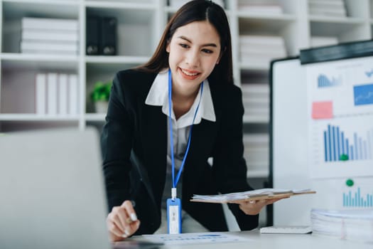 Beautiful young teen asian businesswoman using laptop computer and paperworks with planning working on financial document, tax, exchange, accounting and Financial advisor.