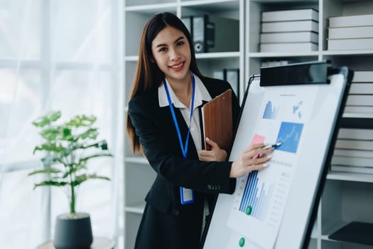 Portrait of young asian woman holding notebook with presentation of strategy, investment plan and marketing