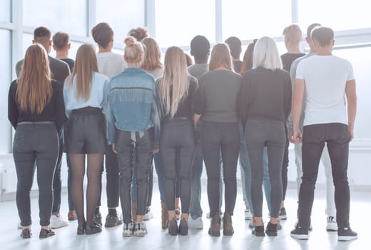 rear view. a large group of young people looking at a large white screen. photo with copy space