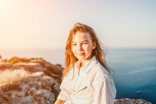 Brown-haired young romantic teenager girl corrects long hair on beach at summer evening wind