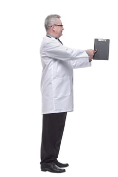 Doctor is wearing white uniform and a tie withe clipboard, stands on a light white background and pointed at camera