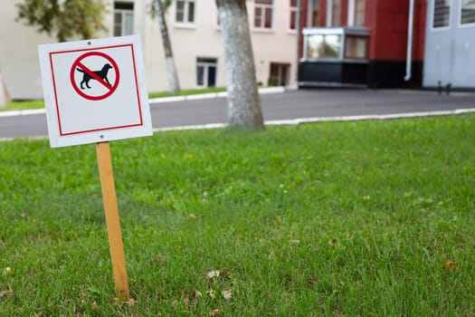Sign prohibiting dogs from walking on lawn is stuck in ground. Special area restricting walking with dogs. Prohibition sign for dog owners