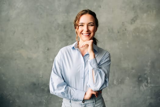 Professional young woman in a blue shirt smiling confidently. Perfect for portraying success, professionalism, and positive business environments. Ideal for business-related and corporate imagery