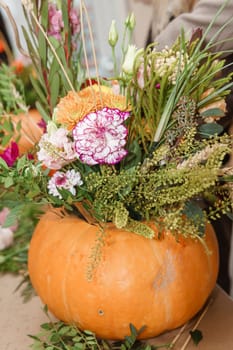 Flower arrangement in a pumpkin, autumn interior decor. Creating handmade autumn decor