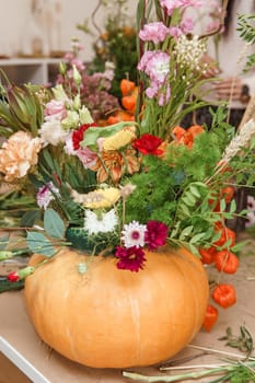 Flower arrangement in a pumpkin, autumn interior decor. Creating handmade autumn decor
