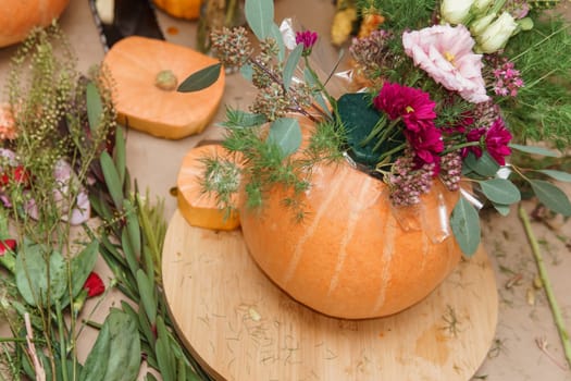 Flower arrangement in a pumpkin, autumn interior decor. Creating handmade autumn decor