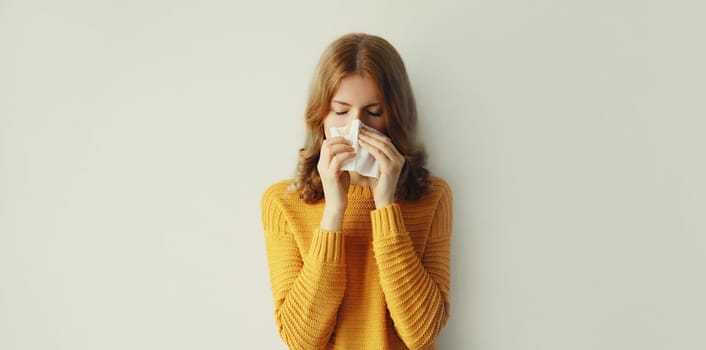 Sick exhausted young woman sneezing blow nose using tissue, unhealthy suffering girl feels unwell at home