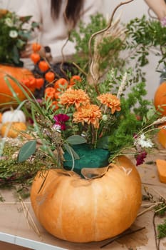 Flower arrangement in a pumpkin, autumn interior decor. Creating handmade autumn decor