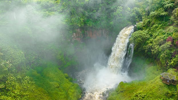 Telun Berasap Falls in green forest. Waterfall in the tropical mountain jungle. Sumatra, Jambi, Indonesia.