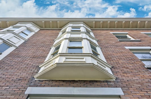 Brick wall of heritage residential building in Vancouver on cloudy sky background.
