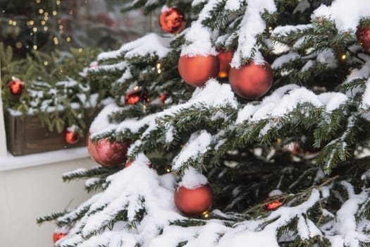 Christmas trees decorated with red balloons in front of the cafe entrance. Street New Year decorations.