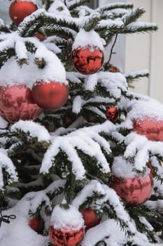 Christmas trees decorated with red balloons in front of the cafe entrance. Street New Year decorations.