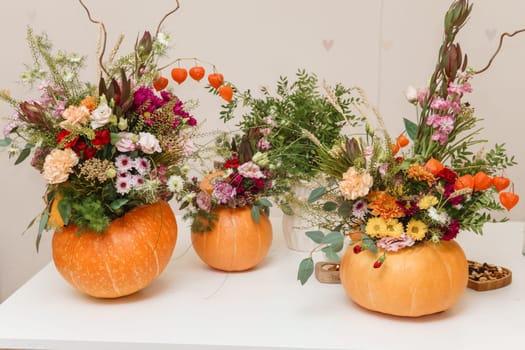 Flower arrangement in a pumpkin, autumn interior decor. Creating handmade autumn decor