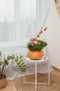 Flower arrangement in a pumpkin, autumn interior decor. Creating handmade autumn decor