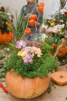 Flower arrangement in a pumpkin, autumn interior decor. Creating handmade autumn decor
