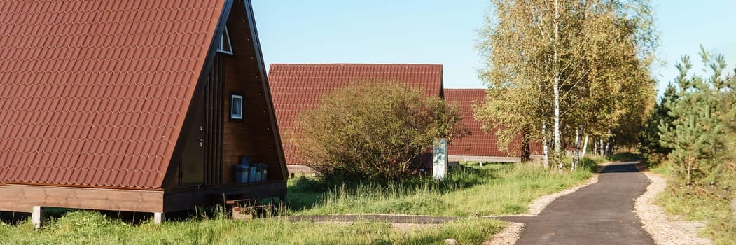 The concept of glamping and renting a chalet for weekend. Wooden house with a veranda in nature around coniferous trees.
