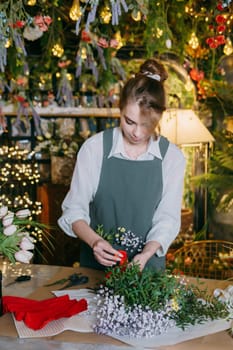 A woman in her florist shop collects bouquets of flowers. The concept of a small business. Bouquets of tulips for the holiday on March 8
