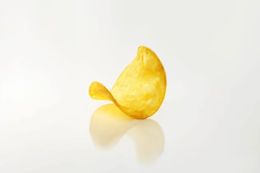 Single crispy potato chip snack isolated on white background with reflection