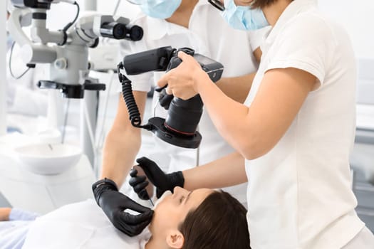 Two professional dentists taking photo of patient teeth in modern dental clinic, using camera