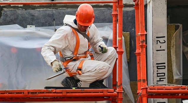 A builder measures the area wearing helmets, goggles and protective equipment at a construction site indoors. Installation of apartment insulation.