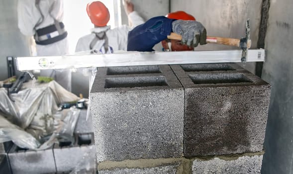 A bricklayer builder lays a block wall at the construction site of an apartment building.