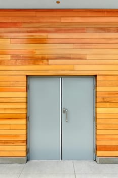 Double-swinging door in a building with wooden siding of the wall.