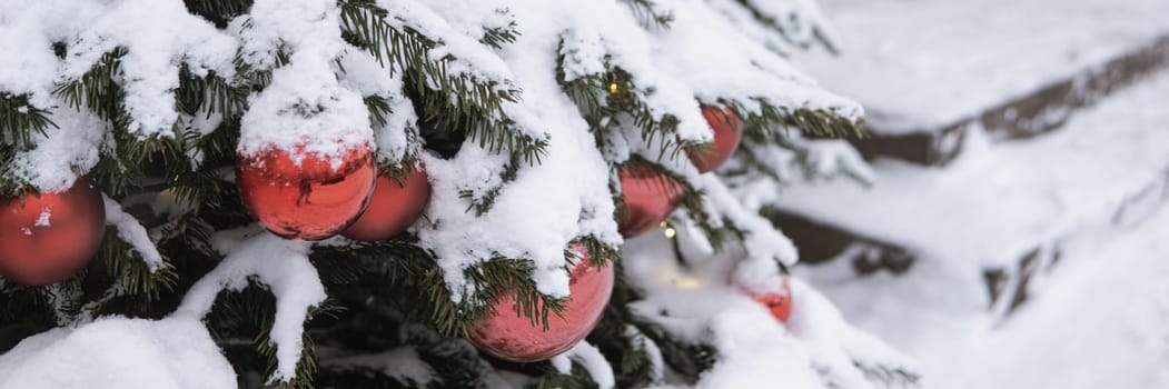 Christmas trees decorated with red balloons in front of the cafe entrance. Street New Year decorations.