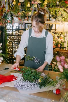 A woman in her florist shop collects bouquets of flowers. The concept of a small business. Bouquets of tulips for the holiday on March 8