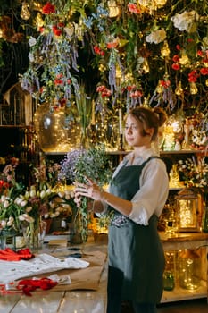 A woman in her florist shop collects bouquets of flowers. The concept of a small business. Bouquets of tulips for the holiday on March 8