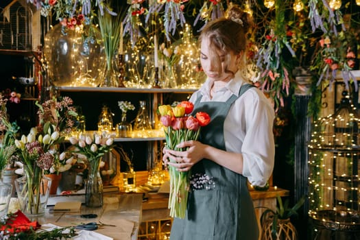 A woman in her florist shop collects bouquets of flowers. The concept of a small business. Bouquets of tulips for the holiday on March 8