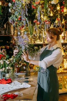 A woman in her florist shop collects bouquets of flowers. The concept of a small business. Bouquets of tulips for the holiday on March 8