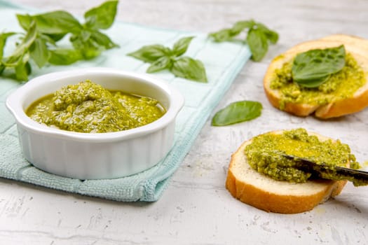 A photo of spreading fresh pesto on small slices of bread in a studio setting.
