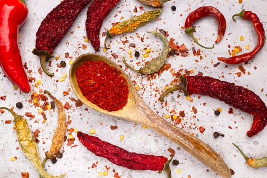 A flat lay photo of peppers in various stages. Fresh, drying, dried, pepper flakes, and pepper powder in a spoon.