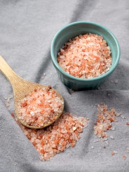A top view of himalayan pink salt on a wooden spoon and in a bowl.