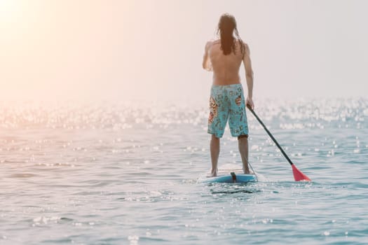 Man Sea Sup. Strong athletic man learns to paddle sup standing on board in open sea ocean on sunny day. Summer holiday vacation and travel concept. Aerial view. Slow motion.