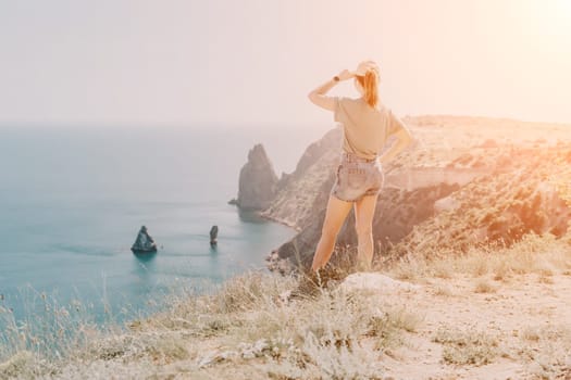 A young woman in a beige shirt and denim shorts gazes at a stunning coastal panorama.