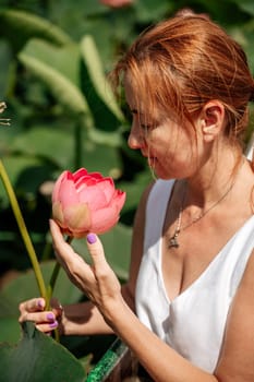 A woman is sitting in a boat in a field of pink lotus flowers