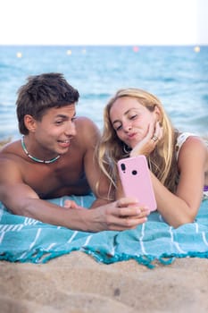 Smiling young woman and man enjoying vacation. Beautiful and cheerfulcoupleof generation z pose for a photo with a mobile phone.