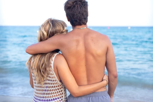 Rear view smiling multiethnic woman and man enjoying vacation. Beautiful and cheerful couple of generation z pose for a photo with a mobile phone.