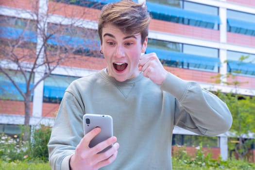 Excited caucasian man using mobile phone watching football match. Student euphoric about the exam result..