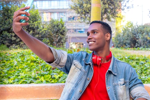 A happy student with headphones on the university campus taking a self-portrait to upload to a social media app