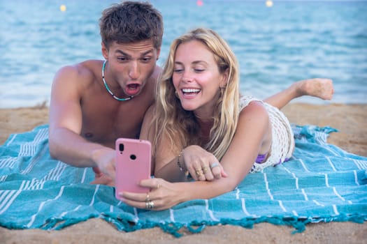 Man and woman hands typing on phone browsing social media phone sitting on beach