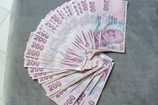 A thick stack of Turkish lira is laid out on a gray velvet table, ready to be counted, 200 Turkish lira bills, the currency for buying real estate,giving up cash and switching to non-cash payments