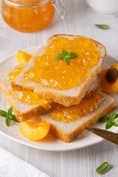 Apricot jam on bread in a white plate.