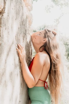 Woman travel sea. Young Happy woman in a long red dress posing on a beach near the sea on background of volcanic rocks, like in Iceland, sharing travel adventure journey