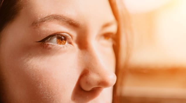 A close-up shot of a woman's eye looking off to the side. The warm light creates a soft, dreamy atmosphere.